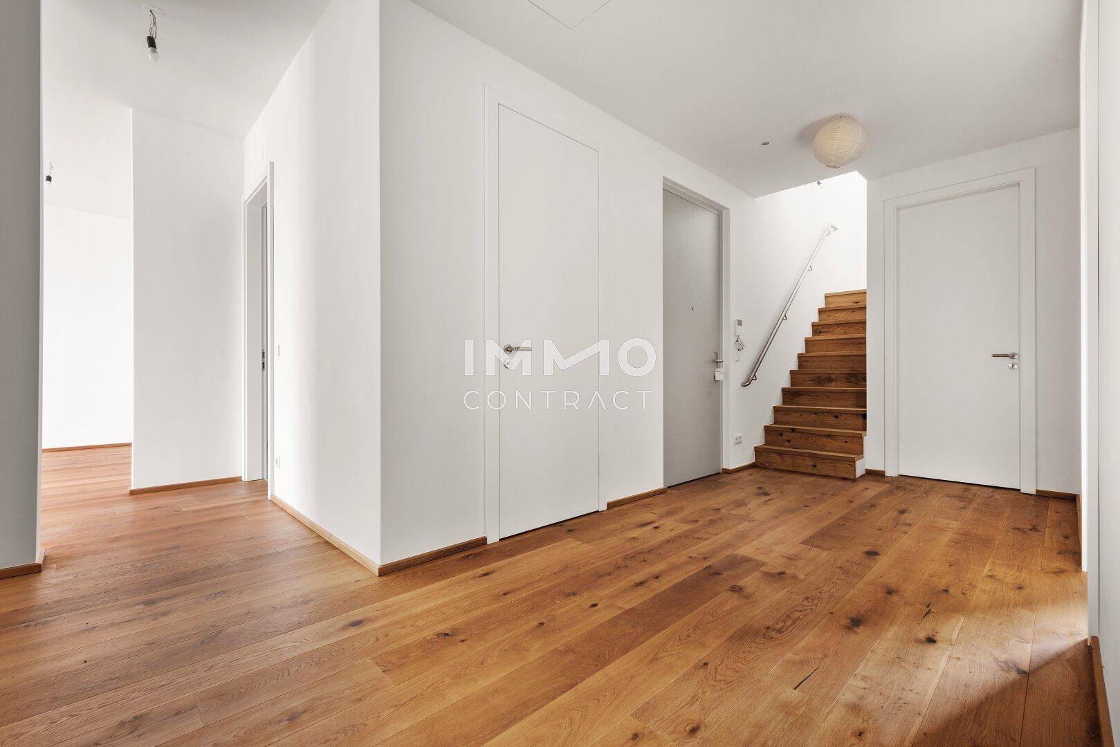 Heller Flur mit Holzboden und einer Holztreppe, die in die obere Etage führt.