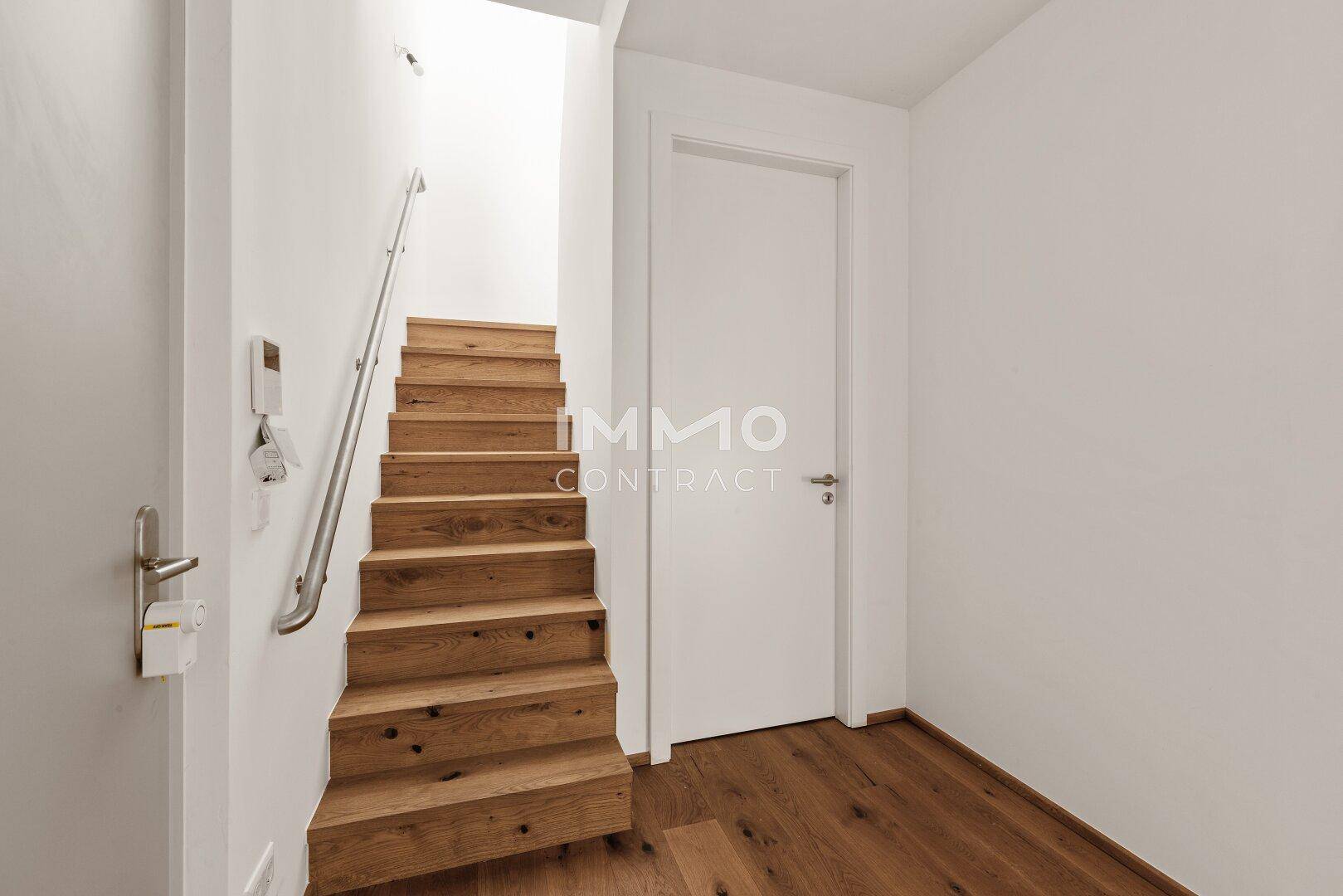 Heller Flur mit Holzboden und einer Holztreppe, die in die obere Etage führt.
