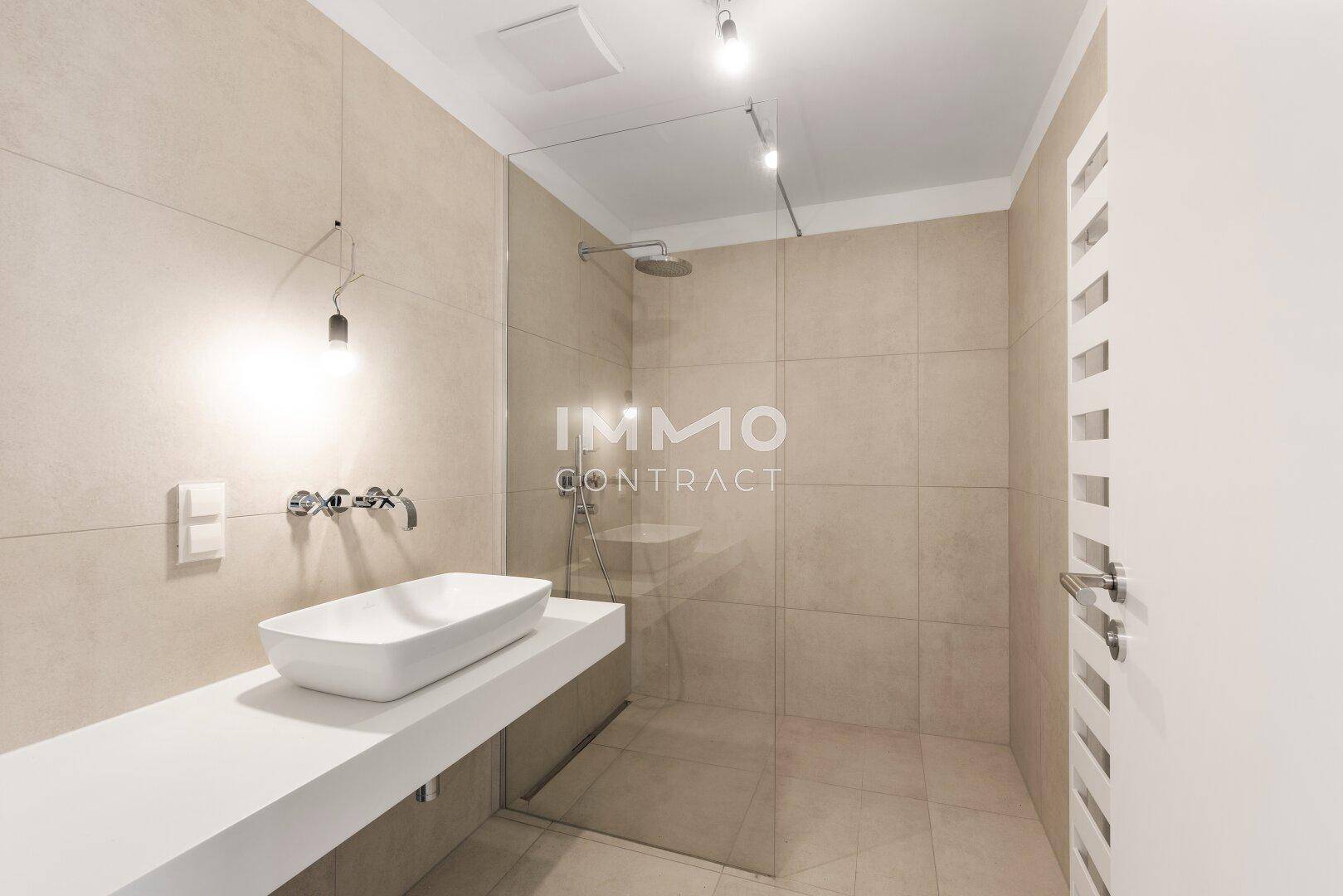 Modernes Badezimmer mit begehbarer Dusche, Einzelwaschbecken und beigefarbenen Wandfliesen.