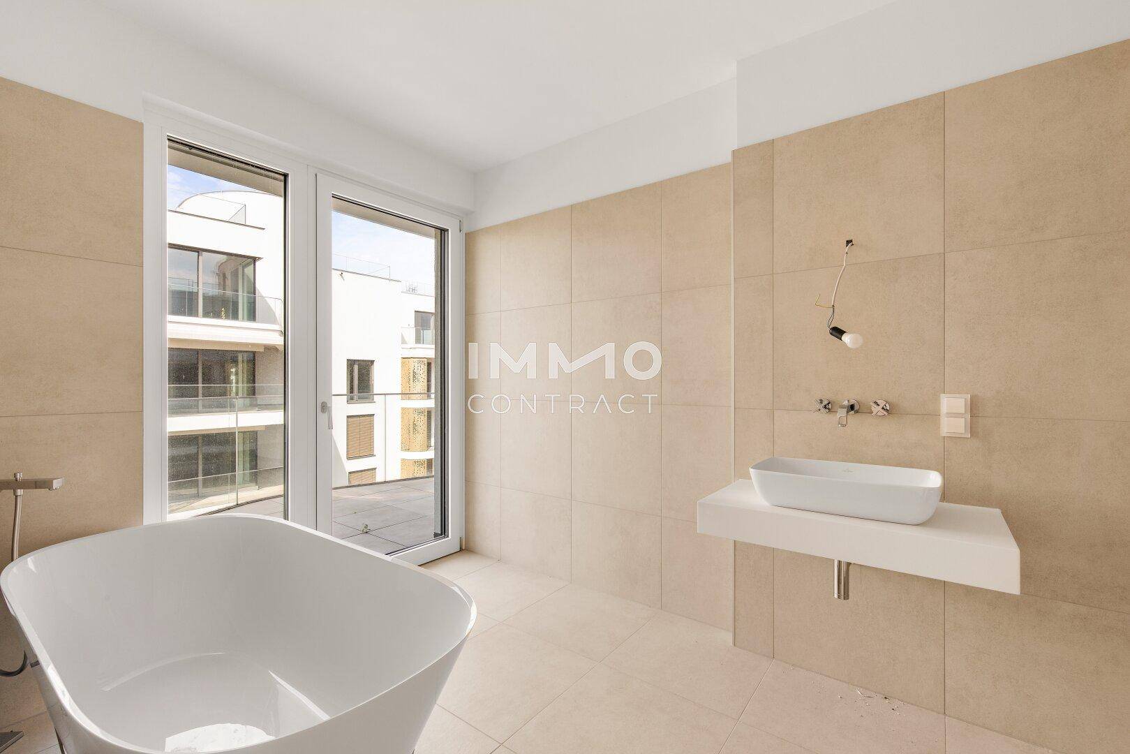 Helles Badezimmer mit Badewanne, Einzelwaschbecken und großem Fenster, das viel Tageslicht hereinlässt.
