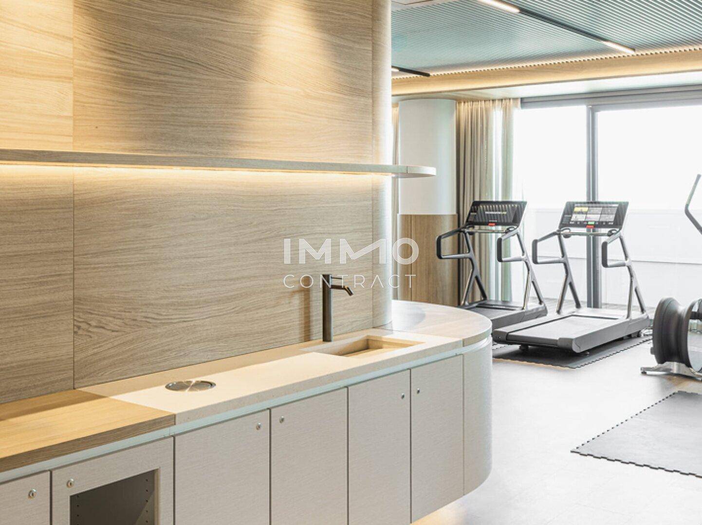 Moderner Fitnessraum mit Laufbändern und einer kleinen Theke für Erfrischungen.