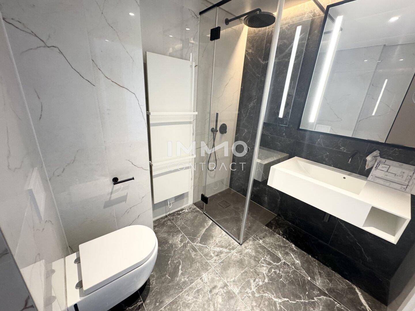 Modernes Badezimmer mit Marmorfliesen, begehbarer Dusche und elegantem Waschtisch.