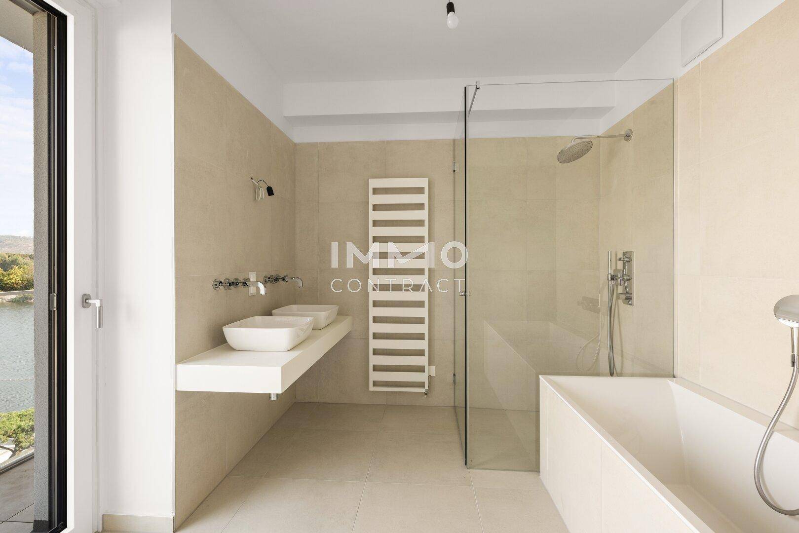 Modernes Badezimmer mit Doppelwaschbecken, Badewanne, begehbarer Dusche und beheiztem Handtuchhalter.