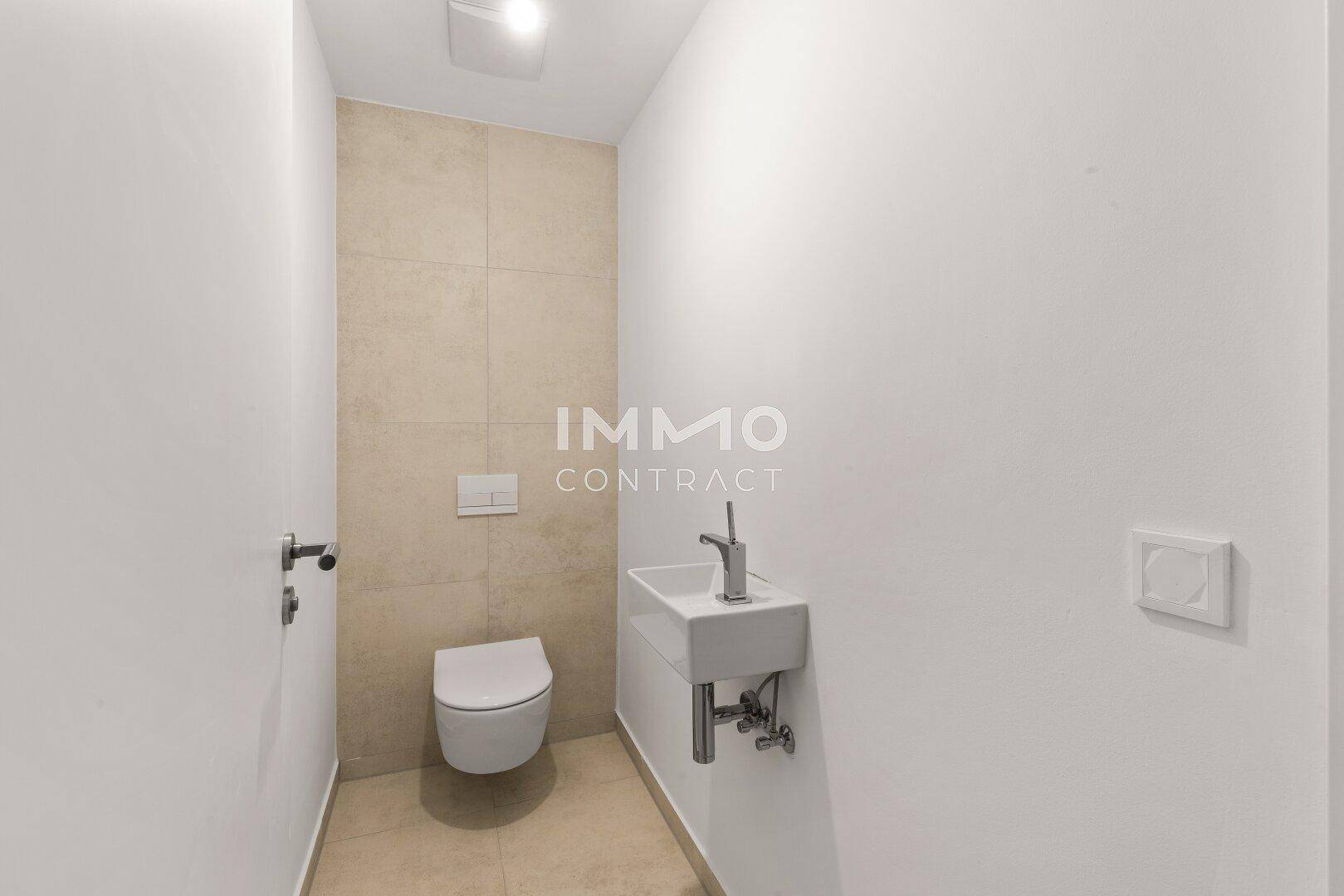 Separates Gäste-WC mit modernem Wand-WC und kleinem Waschbecken in minimalistischem Design.
