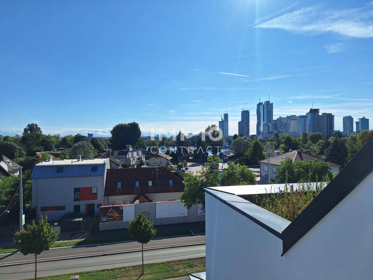 Panoramablick über die Stadt mit modernen Gebäuden und einem See in der Ferne an einem sonnigen Tag.