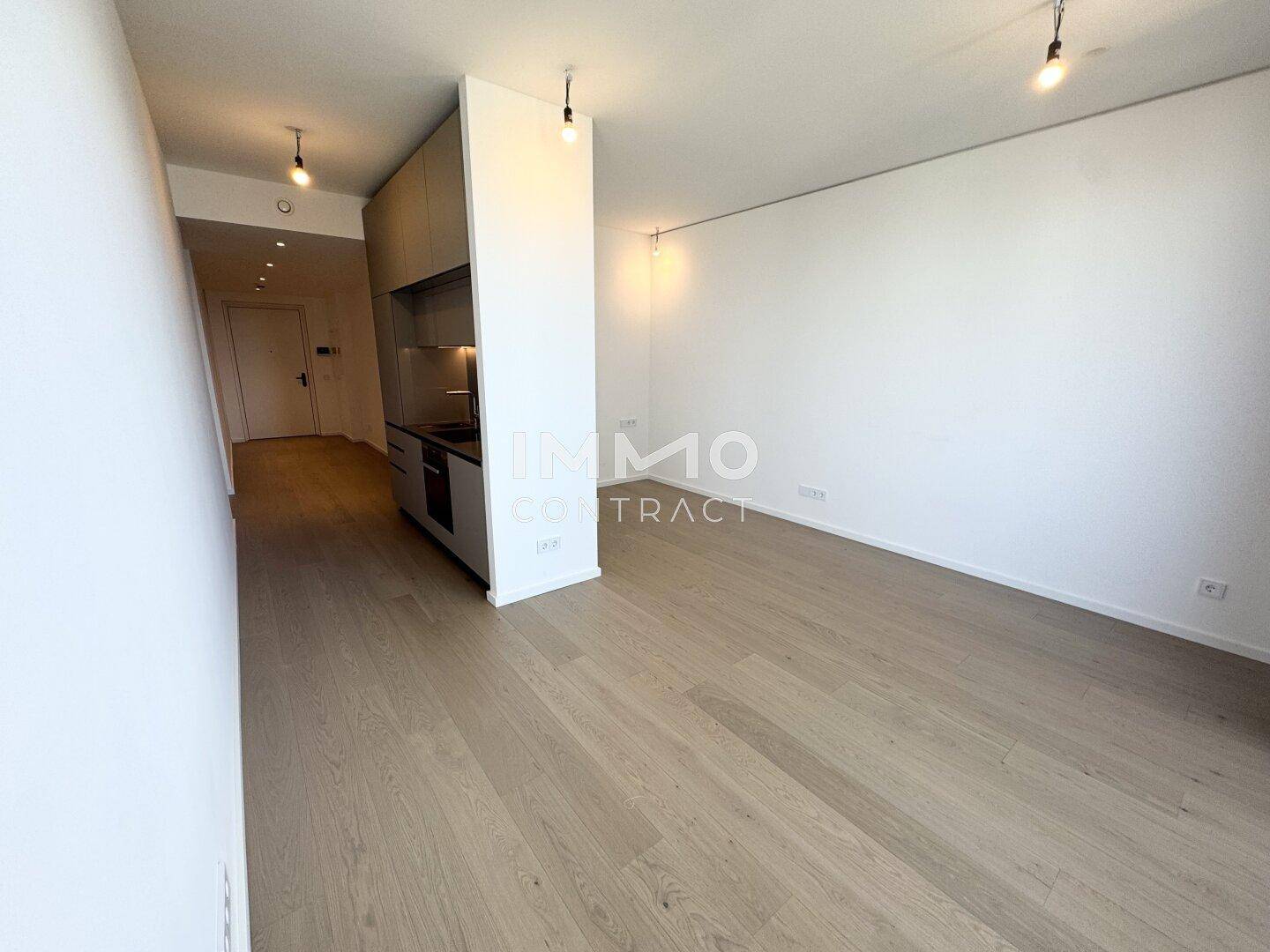 Offener Wohnbereich mit heller Holzoptik und integrierter Küchenzeile, bereit zur Einrichtung.