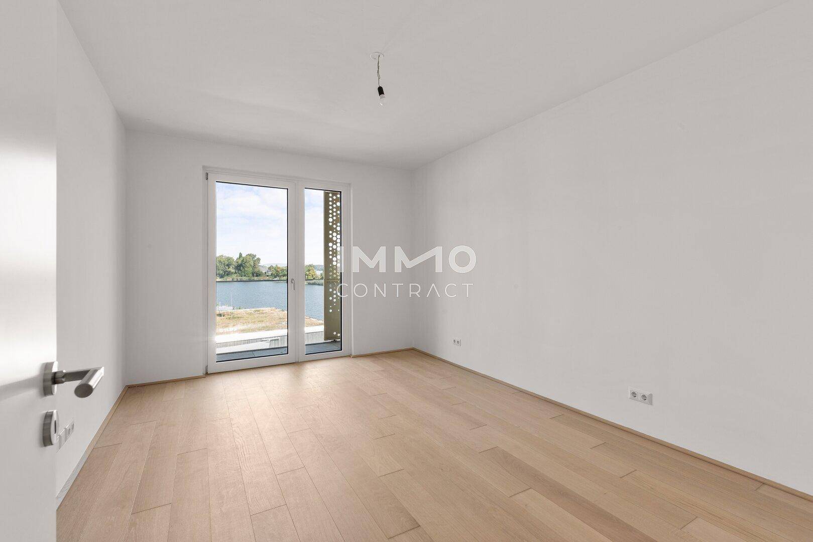 Geräumiges Schlafzimmer mit Holzboden und großen Fenstern, die viel Tageslicht hereinlassen.
