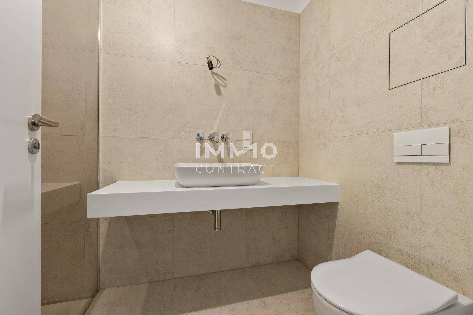 Modernes Badezimmer mit Wand-WC, schwebendem Waschtisch und großformatigen Fliesen.