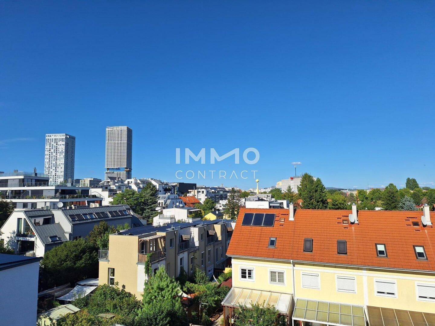 Weitläufiger Blick über die Dächer der Stadt mit modernen Hochhäusern am Horizont an einem sonnigen Tag.