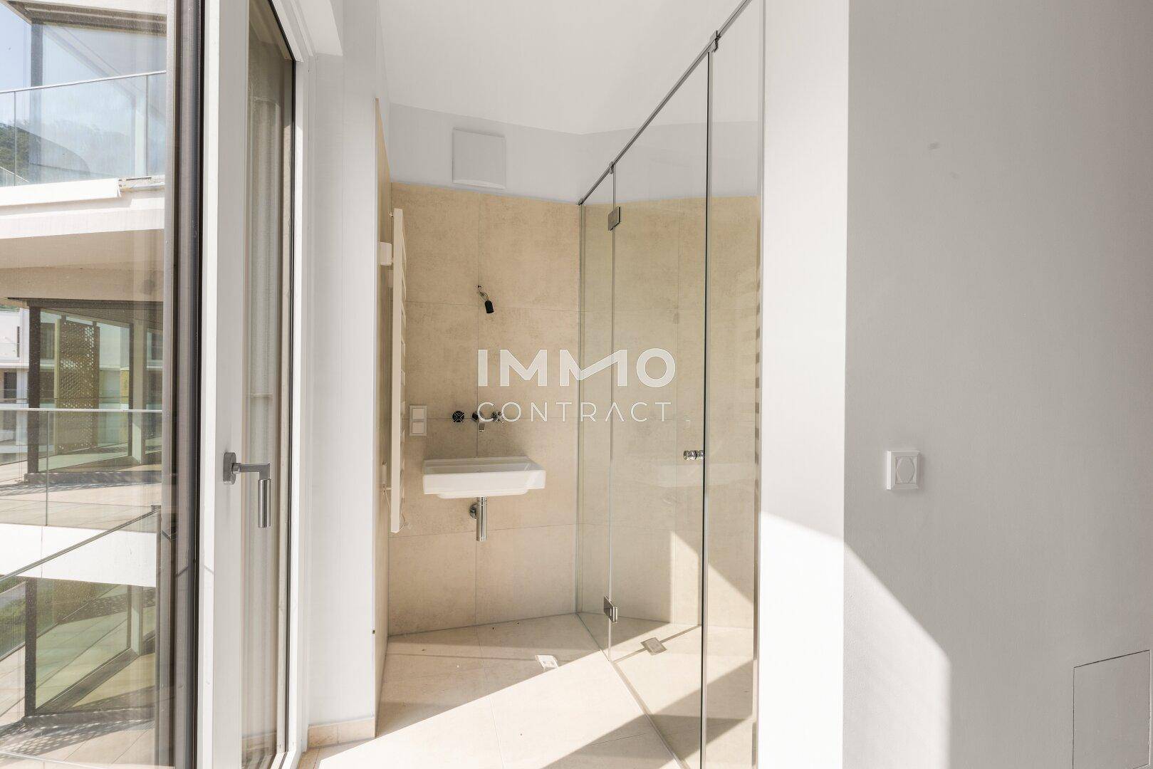 Modernes Badezimmer mit begehbarer Dusche, Waschbecken und großen Fenstern für Tageslicht.