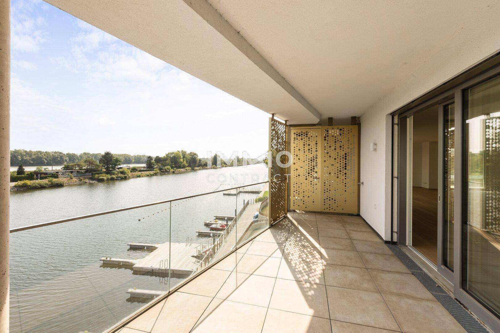 Geräumiger Balkon mit Fliesenboden und weitem Blick auf den Fluss und die umliegende Natur.