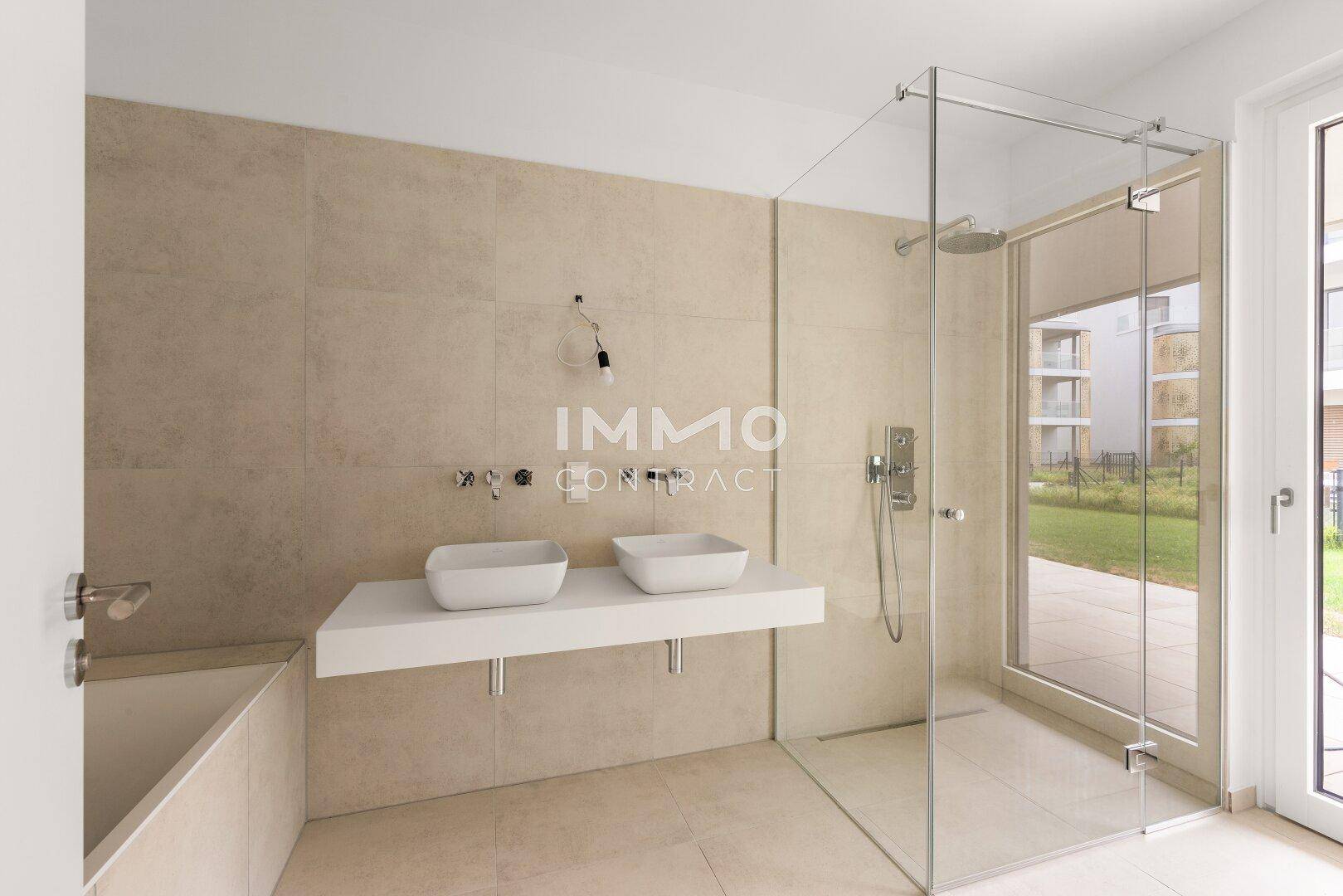 Modernes Badezimmer mit begehbarer Glasdusche, Badewanne und Doppelwaschbecken auf beigefarbenen Fliesen.