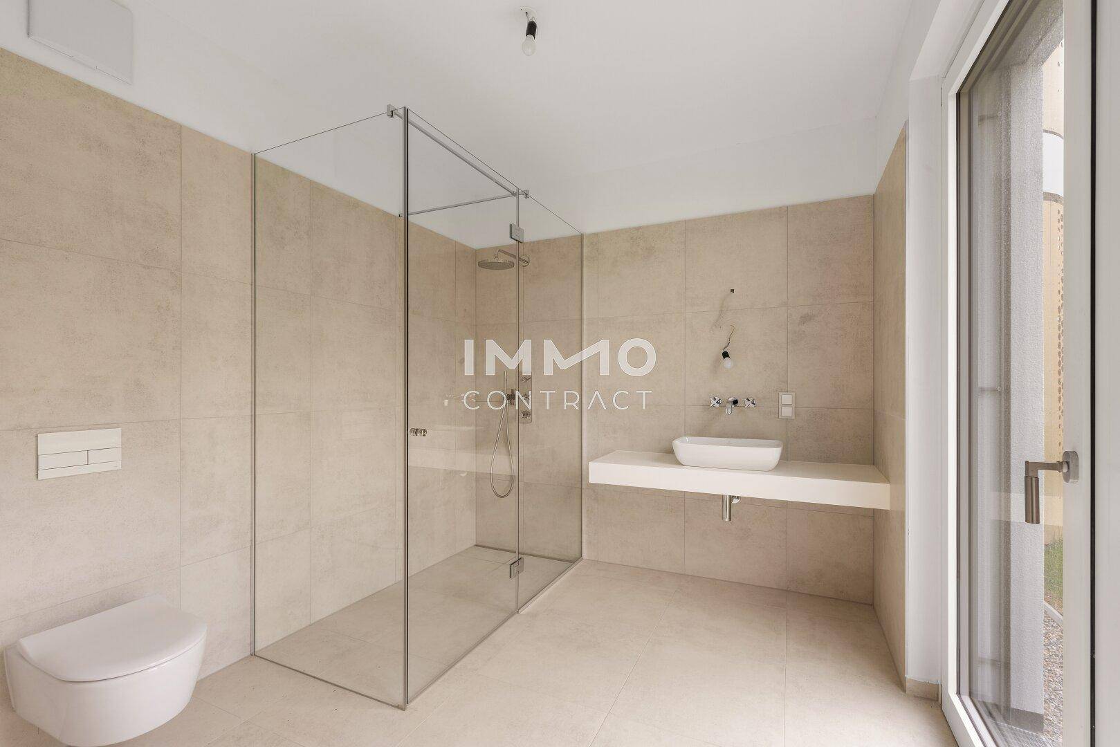 Modernes Badezimmer mit begehbarer Glasdusche, wandhängender Toilette und Einzelwaschbecken auf beigefarbenen Fliesen.