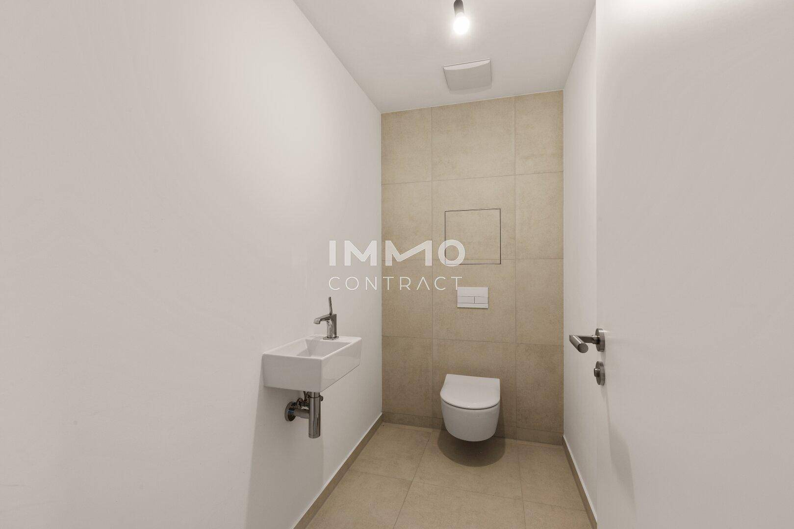 Modernes Gäste-WC mit Wand-WC und kleinem Waschbecken, in neutralen Farbtönen gehalten.