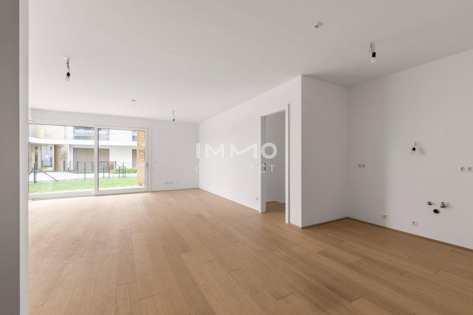 Heller Raum mit Holzboden und Anschlüssen für eine Küche, bereit für die Installation.
