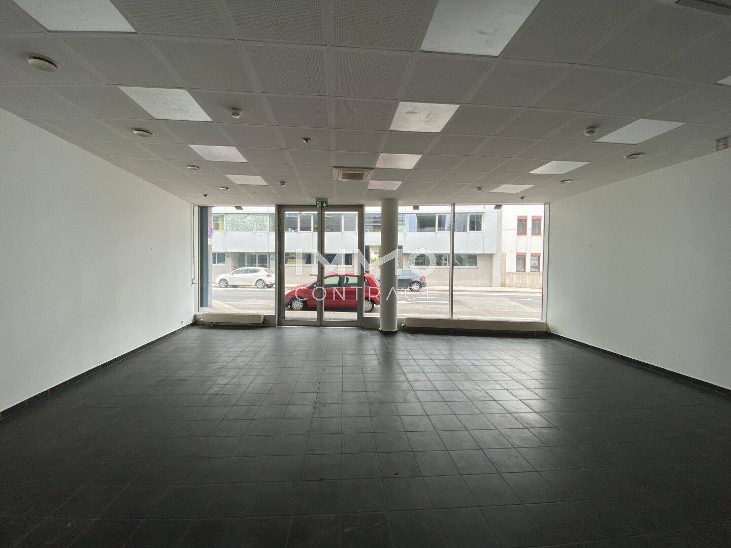 Heller, offener Geschäftsraum mit großen Fensterfronten zur Straße und praktischem Fliesenboden.