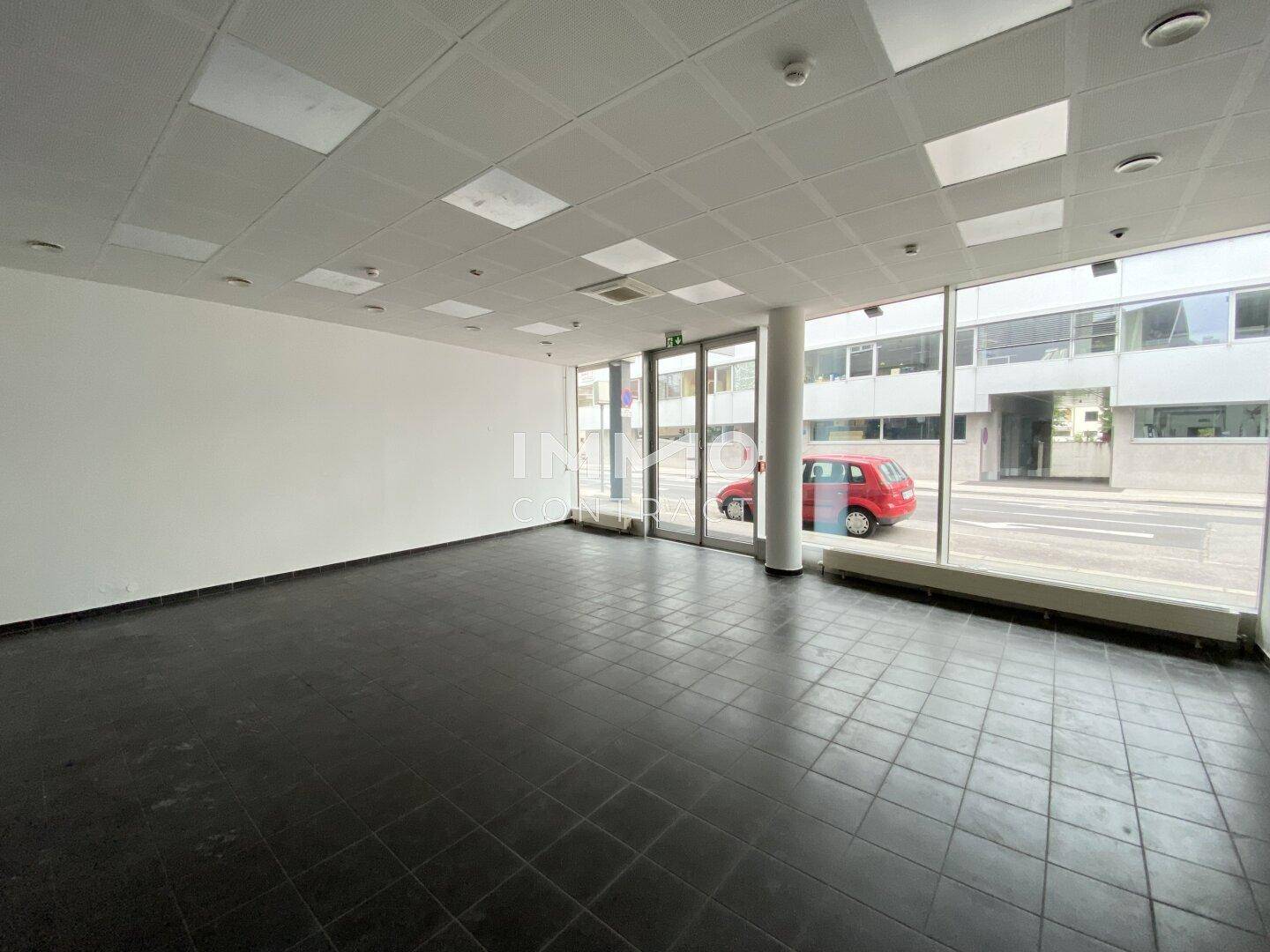 Geräumiger, leerer Geschäftsraum mit großen Schaufenstern und dunklen Fliesenböden, ideal für verschiedene Nutzungsmöglichkeiten.