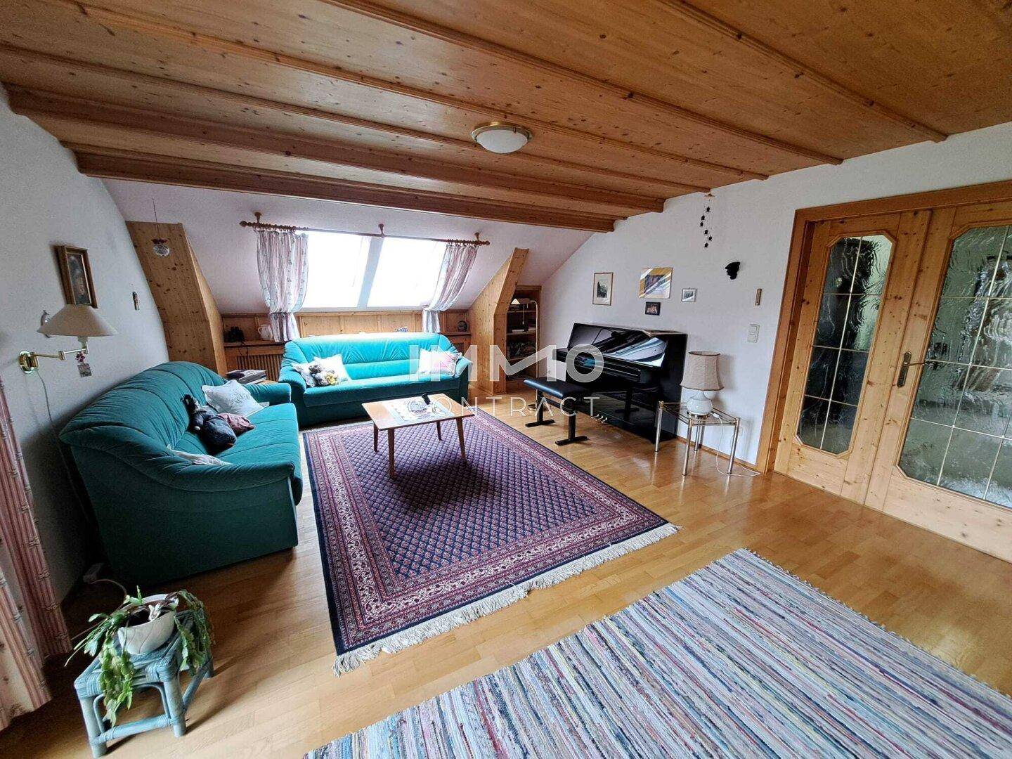 Gemütliches Wohnzimmer im Dachgeschoss mit Holzbalkendecke und Parkettboden.
