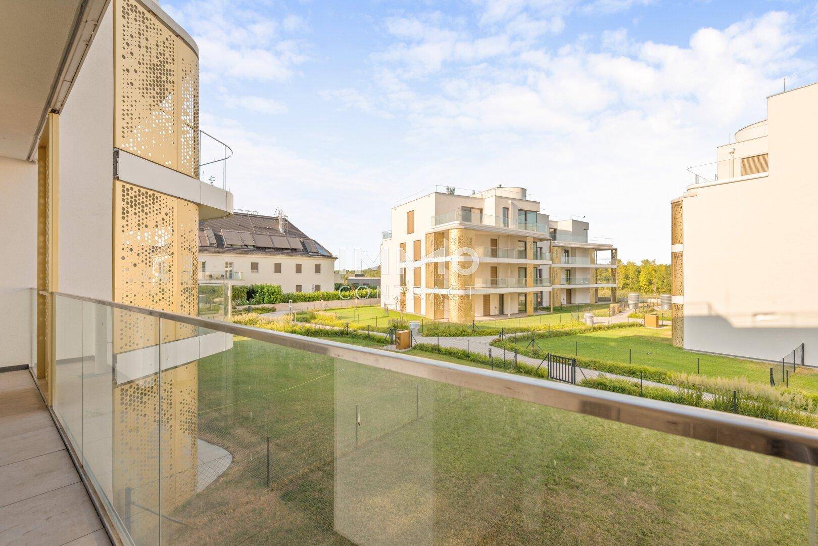 Weitläufiger Blick von der Terrasse auf gepflegte Grünflächen und moderne Wohnanlagen.