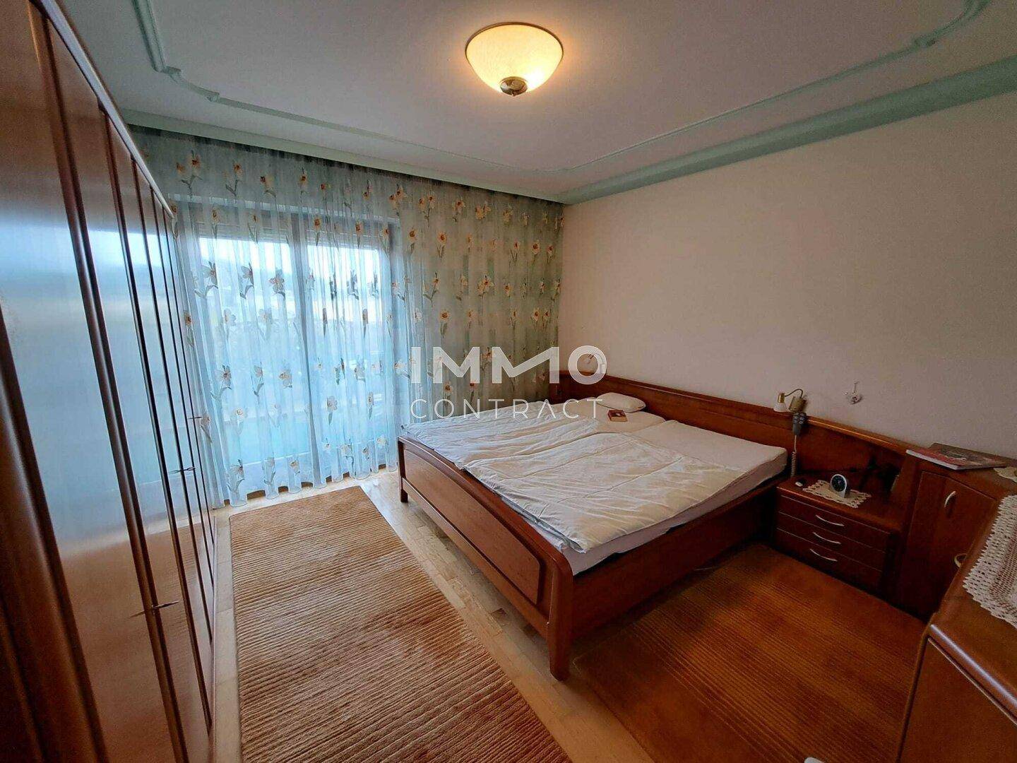 Schlafzimmer mit Holzbett, großem Kleiderschrank und Zugang zum Balkon.