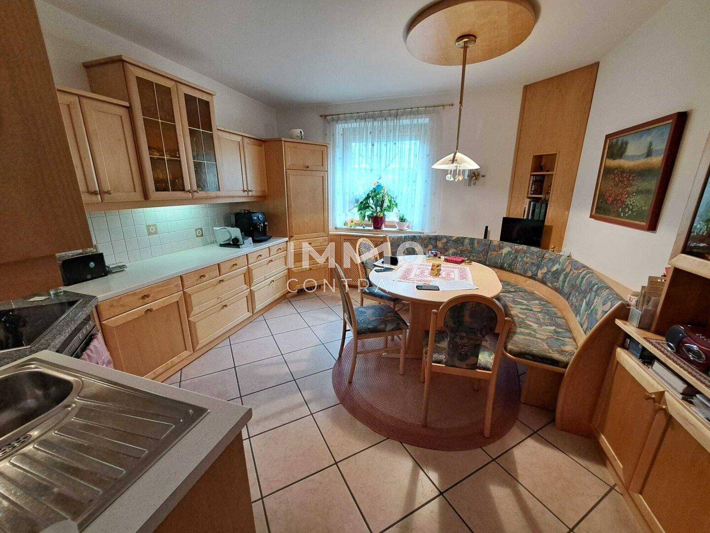 Gemütliche Wohnküche mit Holzeinbauten, Essbereich und Fliesenboden.