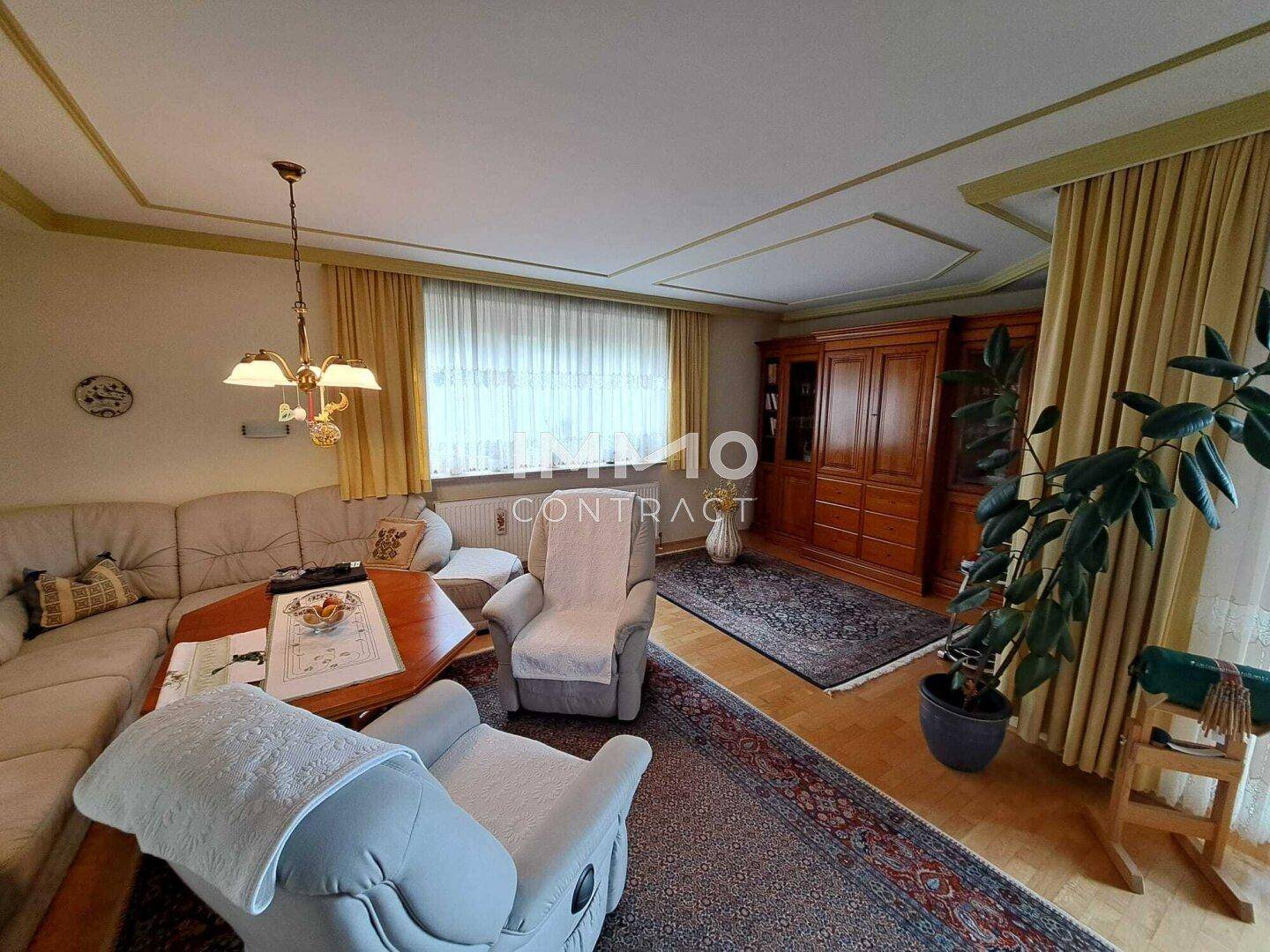 Geräumiges Wohnzimmer mit Parkettboden, Stuckdecke und traditionellen Möbeln.