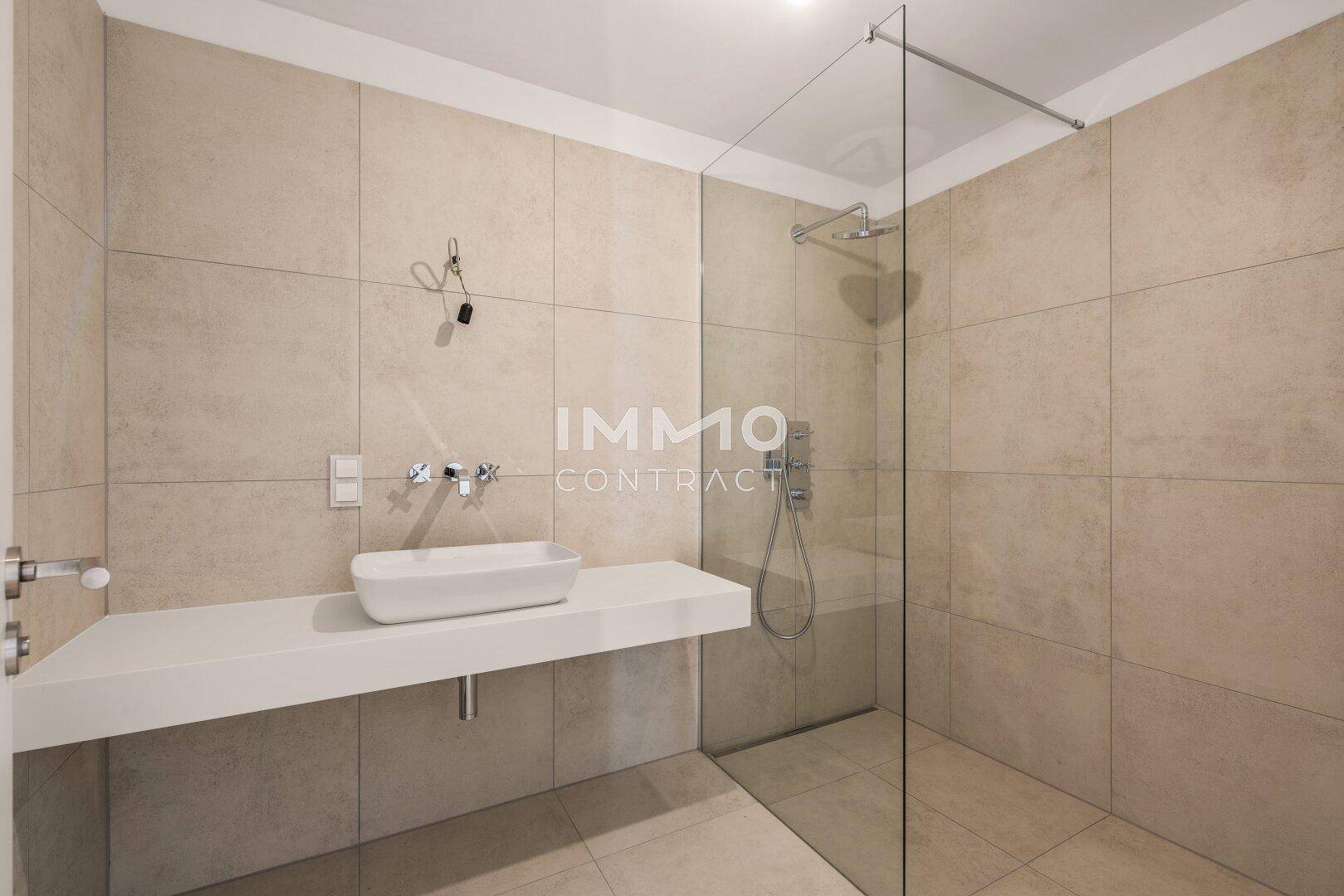 Helles Badezimmer mit modernem Einzelwaschbecken und geräumiger begehbarer Dusche.