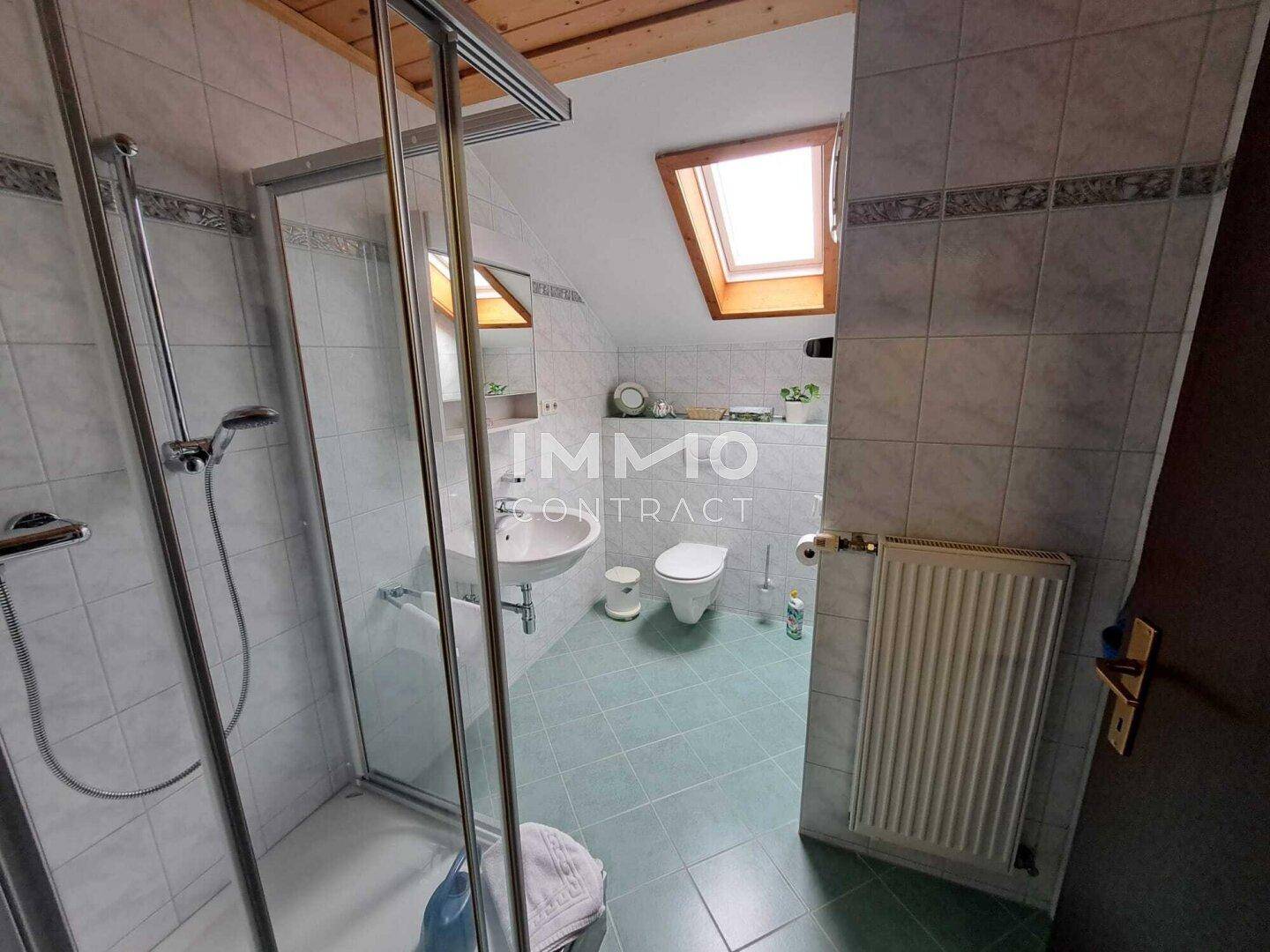 Dachgeschoss-Badezimmer mit Dusche, WC, Waschbecken und Dachfenster.