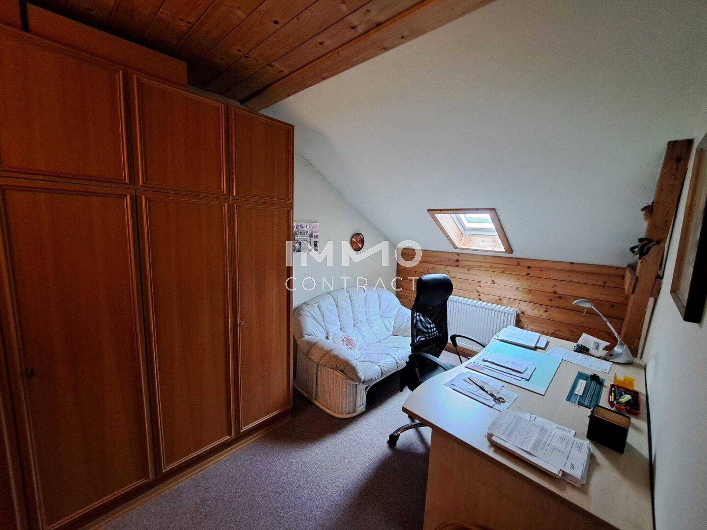 Dachgeschoss-Büro mit Holzverkleidung, Einbauschränken und Dachfenster.