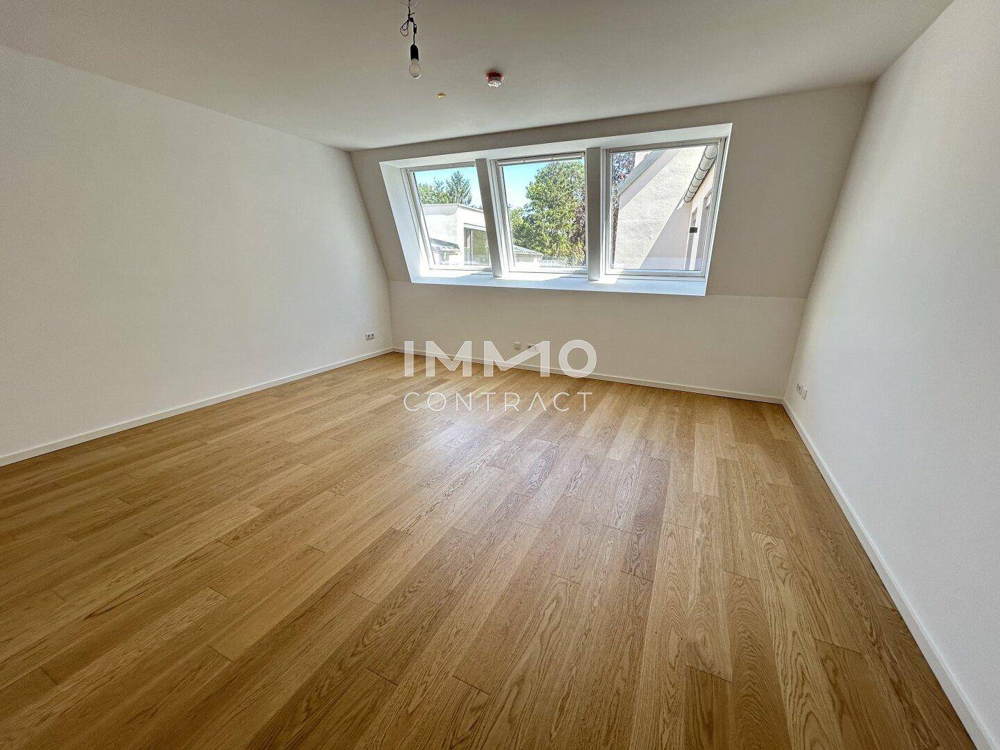 Helles Zimmer mit Holzboden und großen Dachfenstern, ideal als Schlaf- oder Arbeitszimmer.