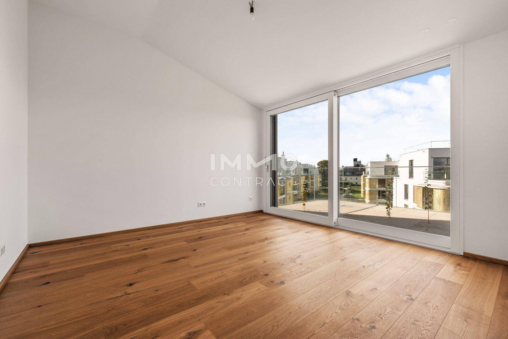 Geräumiges Schlafzimmer mit Holzboden und großen Schiebefenstern, die eine helle Atmosphäre schaffen.