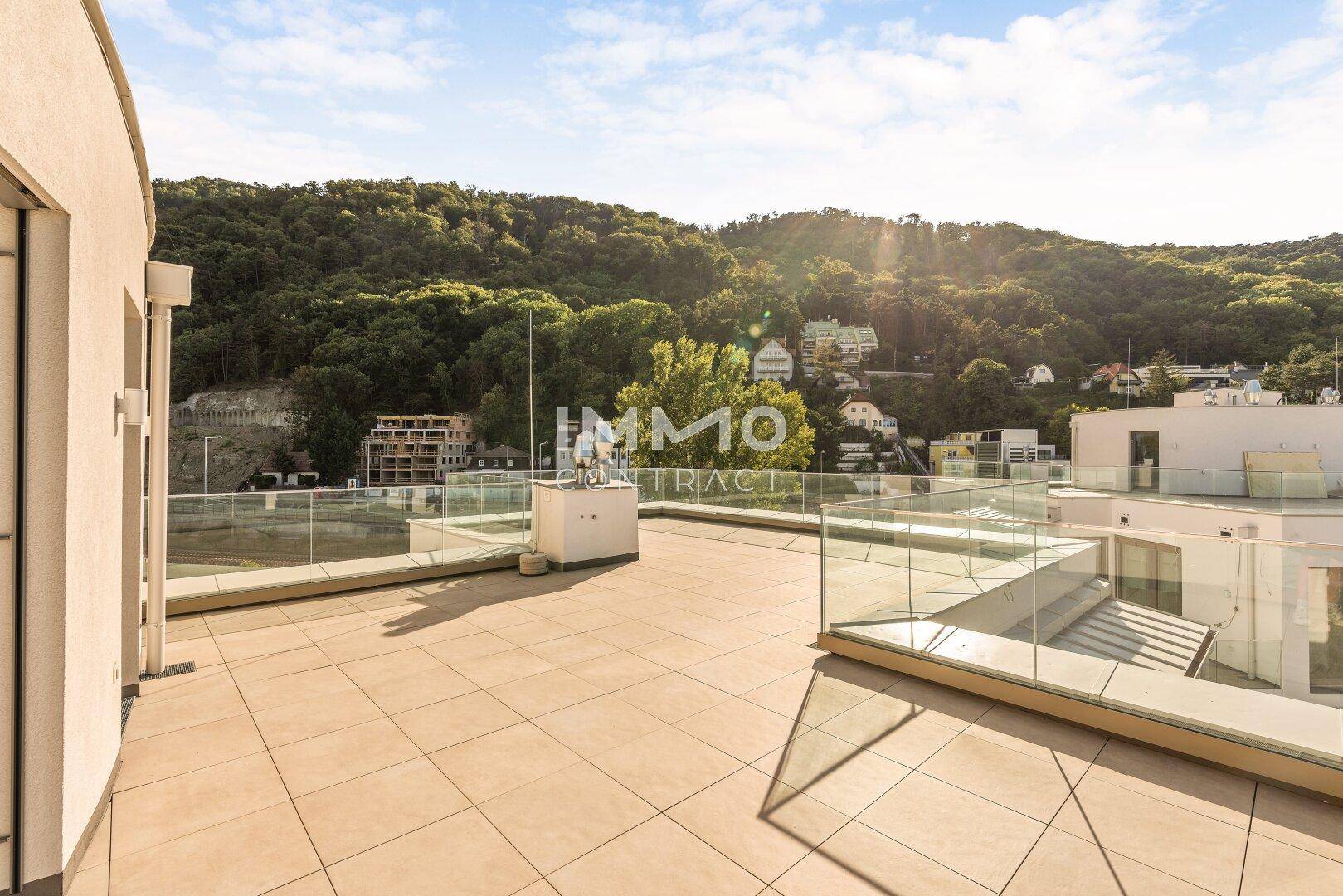 Große Dachterrasse mit Glasgeländer und weitem Blick auf die umliegenden Hügel und die Natur.
