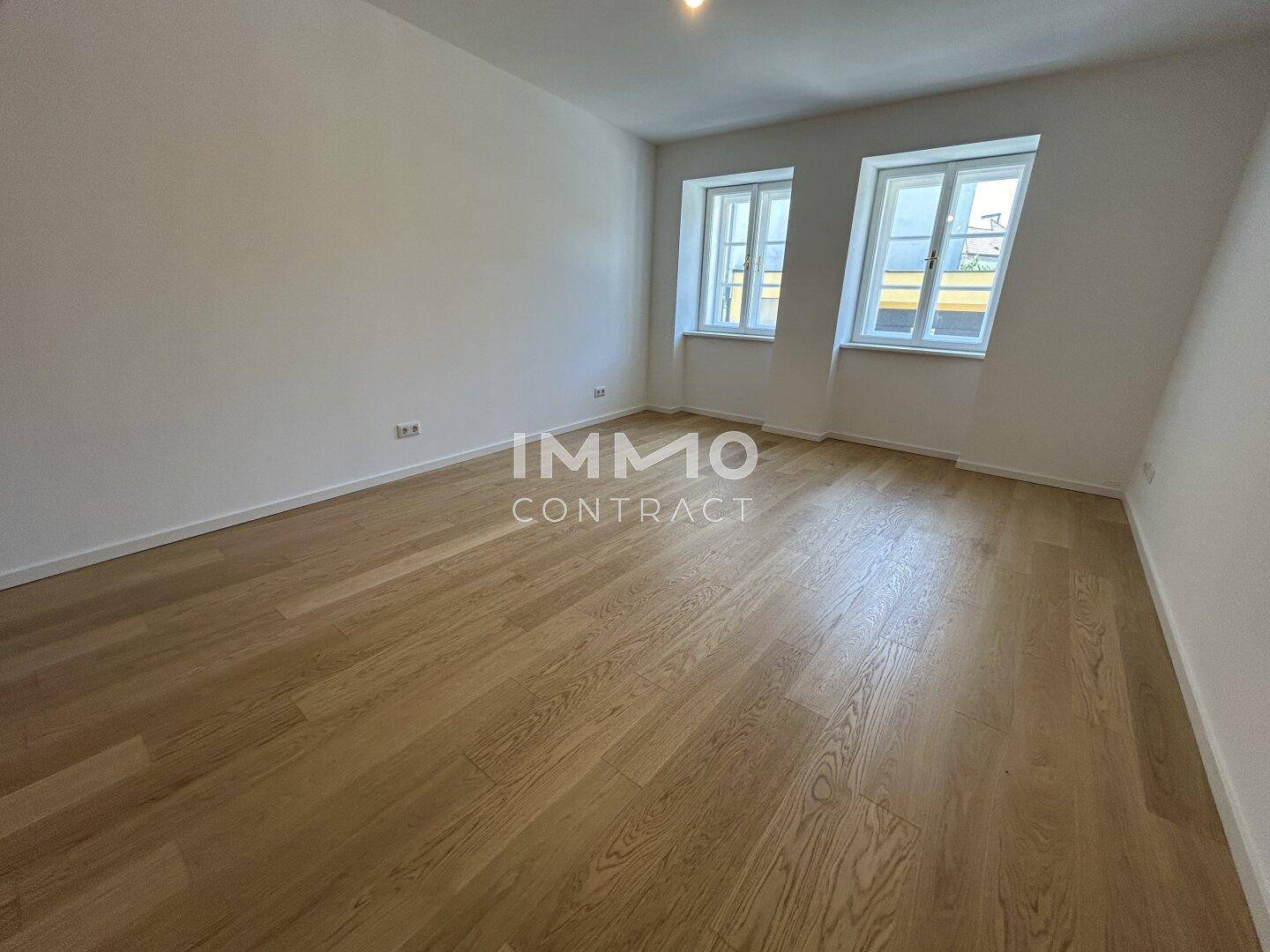 Helles Zimmer mit Holzboden und zwei Fenstern, ideal als Schlaf- oder Kinderzimmer.