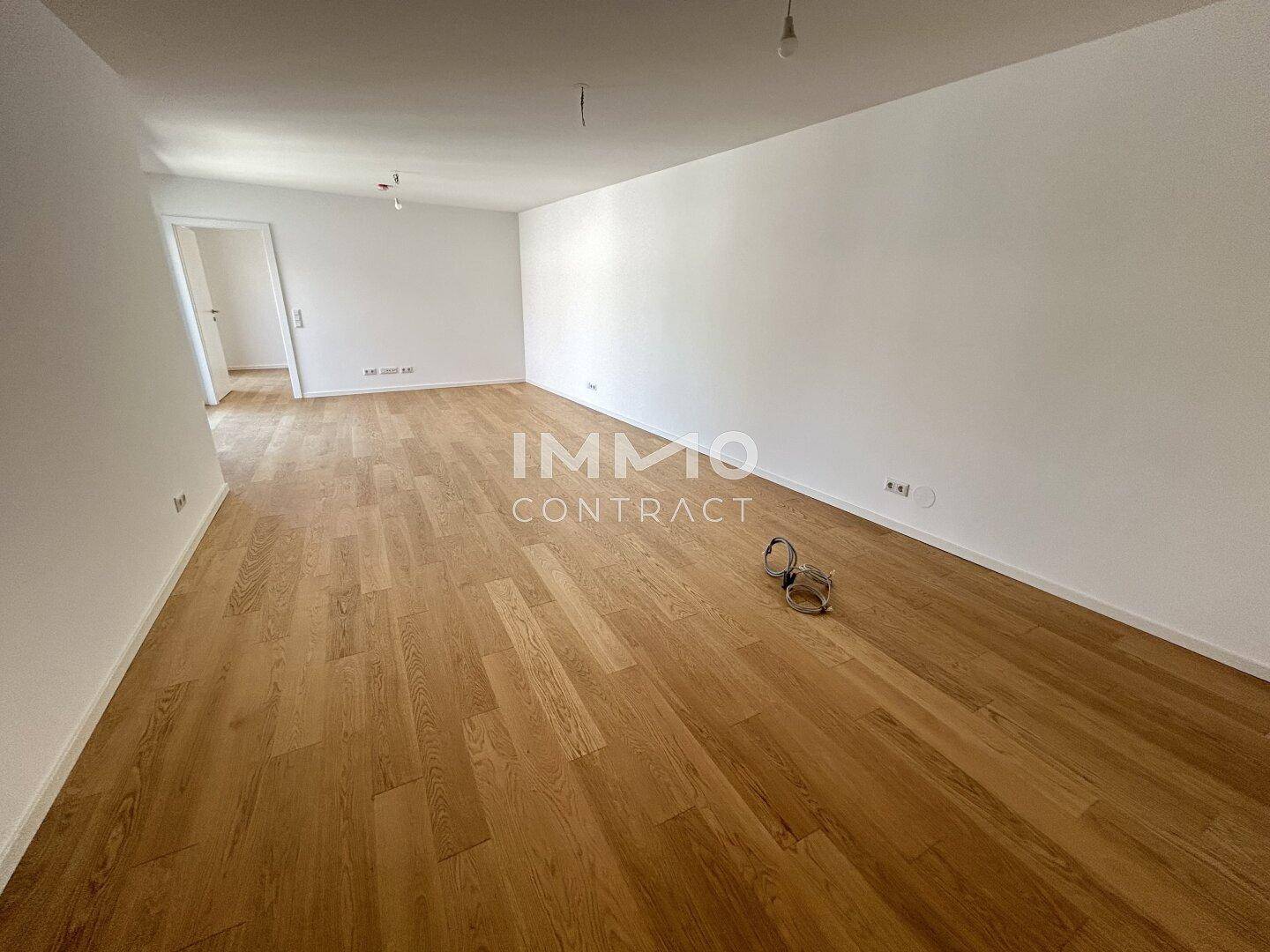 Großzügiger, leerer Raum mit Holzboden und weiß gestrichenen Wänden, vielseitig nutzbar.