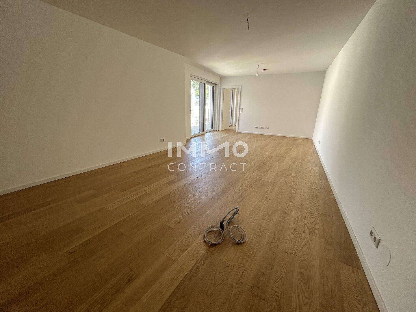 Heller, leerer Raum mit Holzboden und Zugang zu einem weiteren Bereich, ideal für Wohnzwecke.