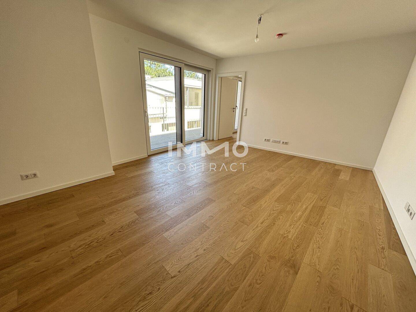 Geräumiges Zimmer mit Holzboden und Schiebetür zum Balkon, vielseitig nutzbar.
