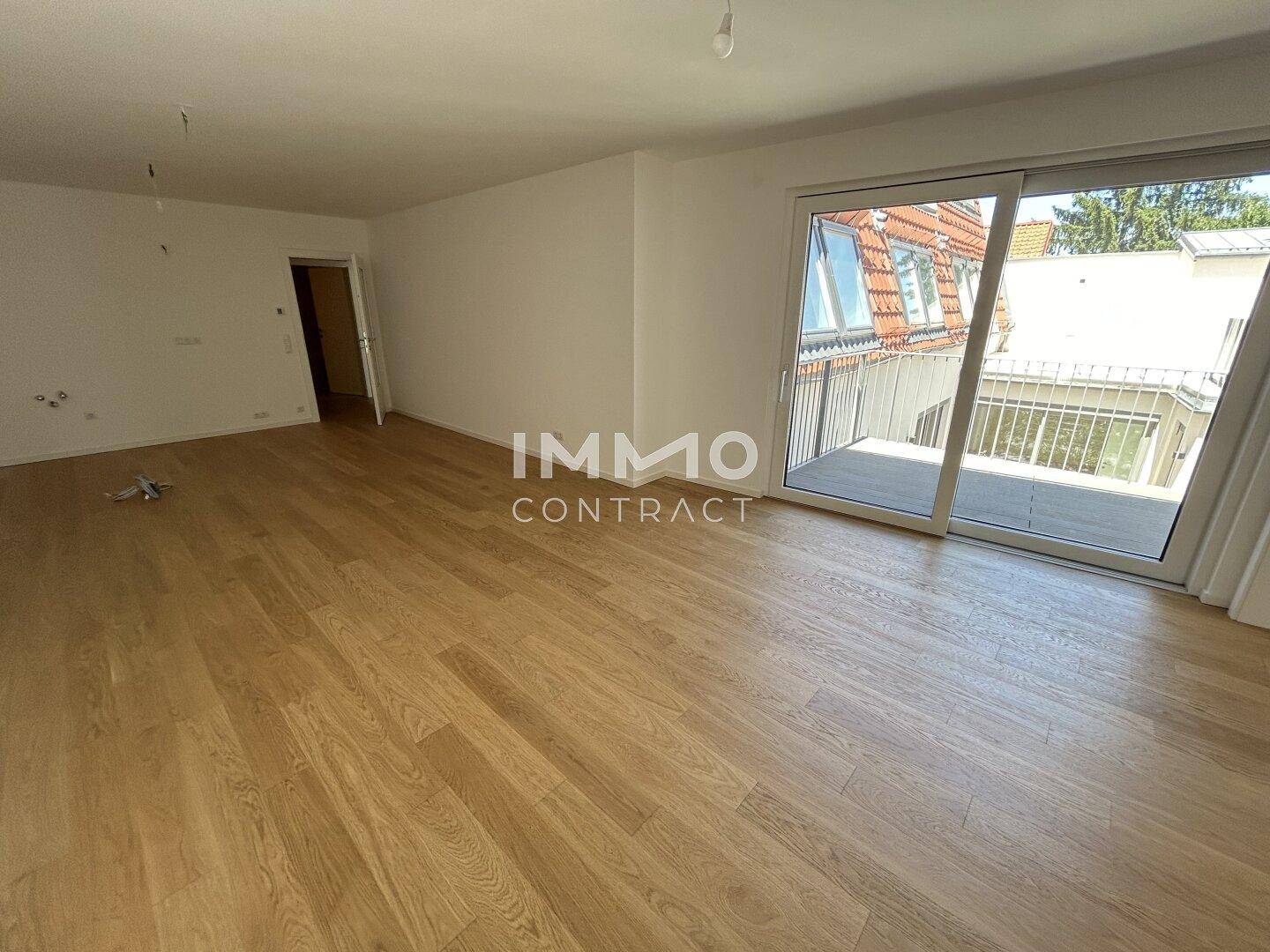 Geräumiges, leeres Zimmer mit Holzboden und Schiebetür zum Balkon, bereit zum Einrichten.
