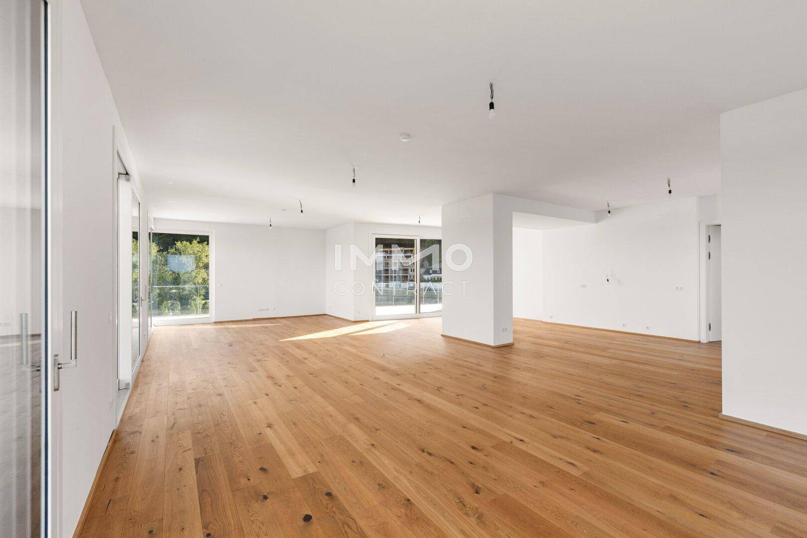 Lichtdurchfluteter Wohnbereich mit modernem Holzboden und Zugang zu einem Außenbereich.