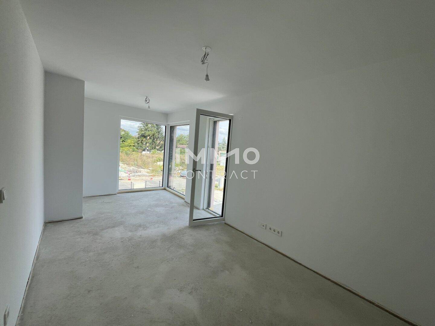 Geräumiges, unfertiges Zimmer mit großen Fenstern, die viel Tageslicht hereinlassen, ideal für Wohnzwecke.