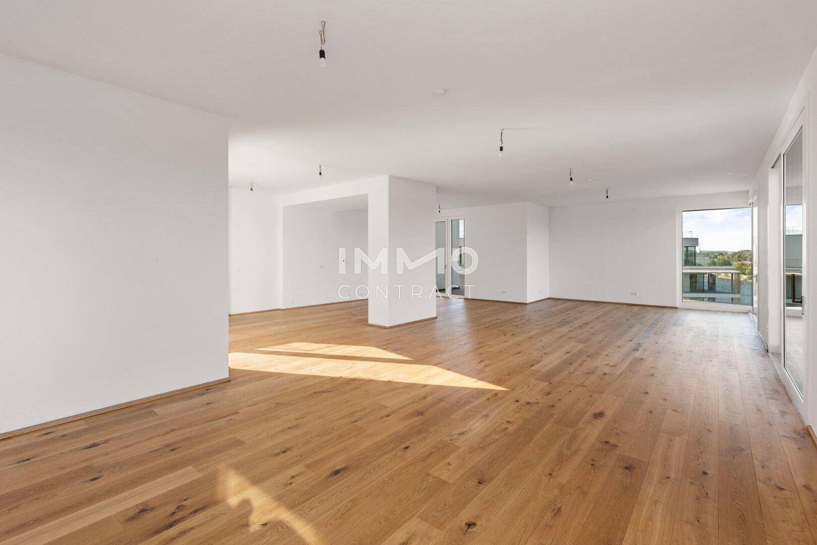 Geräumiger, heller Wohnraum mit Parkettboden und großen Fenstern, die eine moderne Atmosphäre schaffen.
