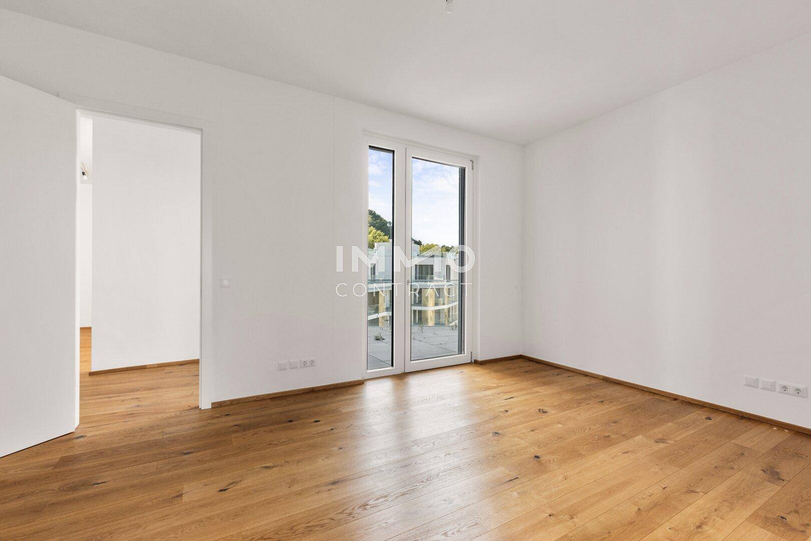 Helles Schlafzimmer mit Holzboden und Zugang zu einem Balkon, bietet einen schönen Ausblick.