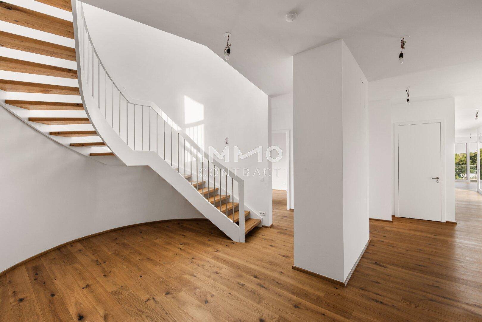 Elegantes Treppenhaus mit geschwungener Form und Holzstufen, das die Etagen stilvoll verbindet.