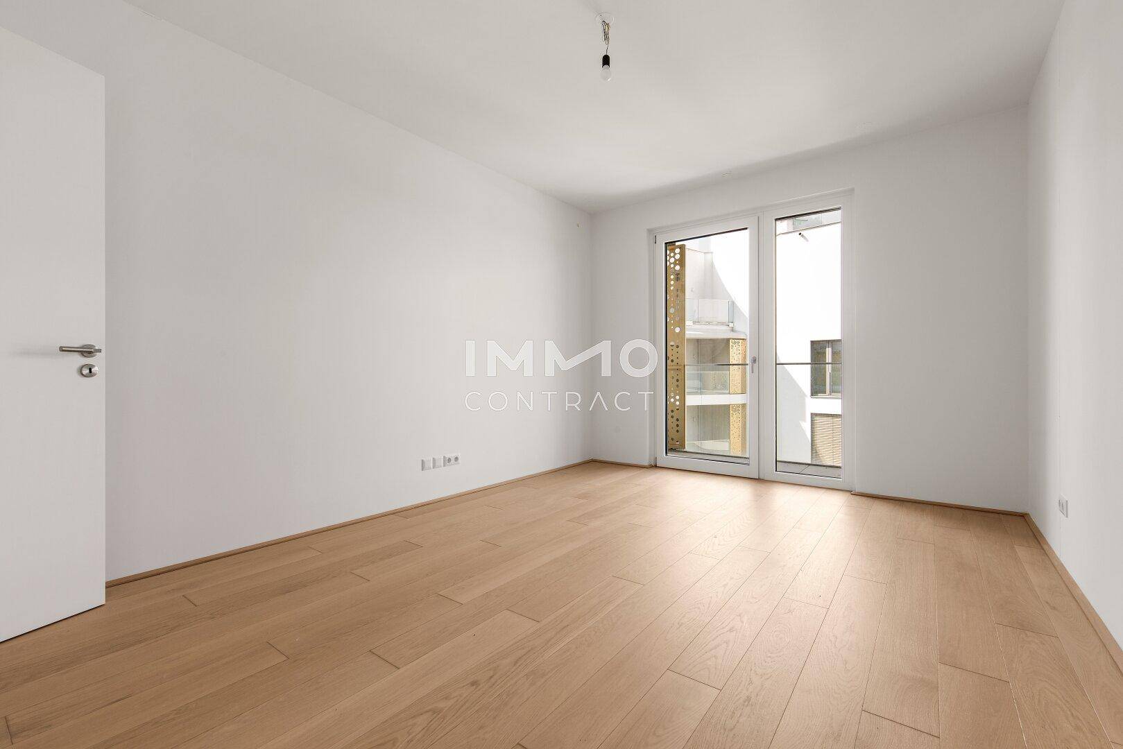 Geräumiges Schlafzimmer mit hellem Parkettboden und Zugang zu einem Außenbereich.