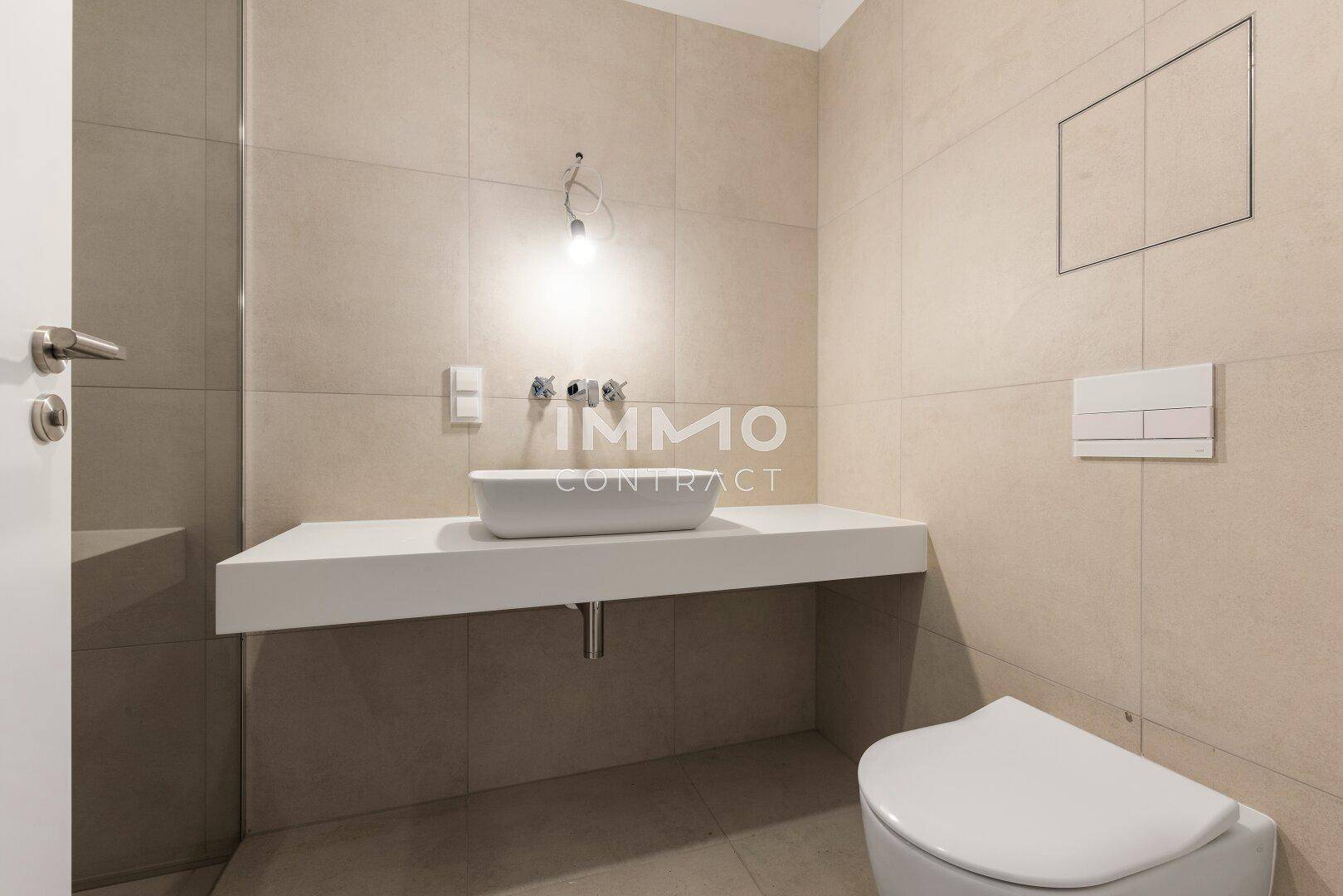 Modernes Badezimmer mit großem Waschtisch, wandhängender Toilette und Fliesenboden.