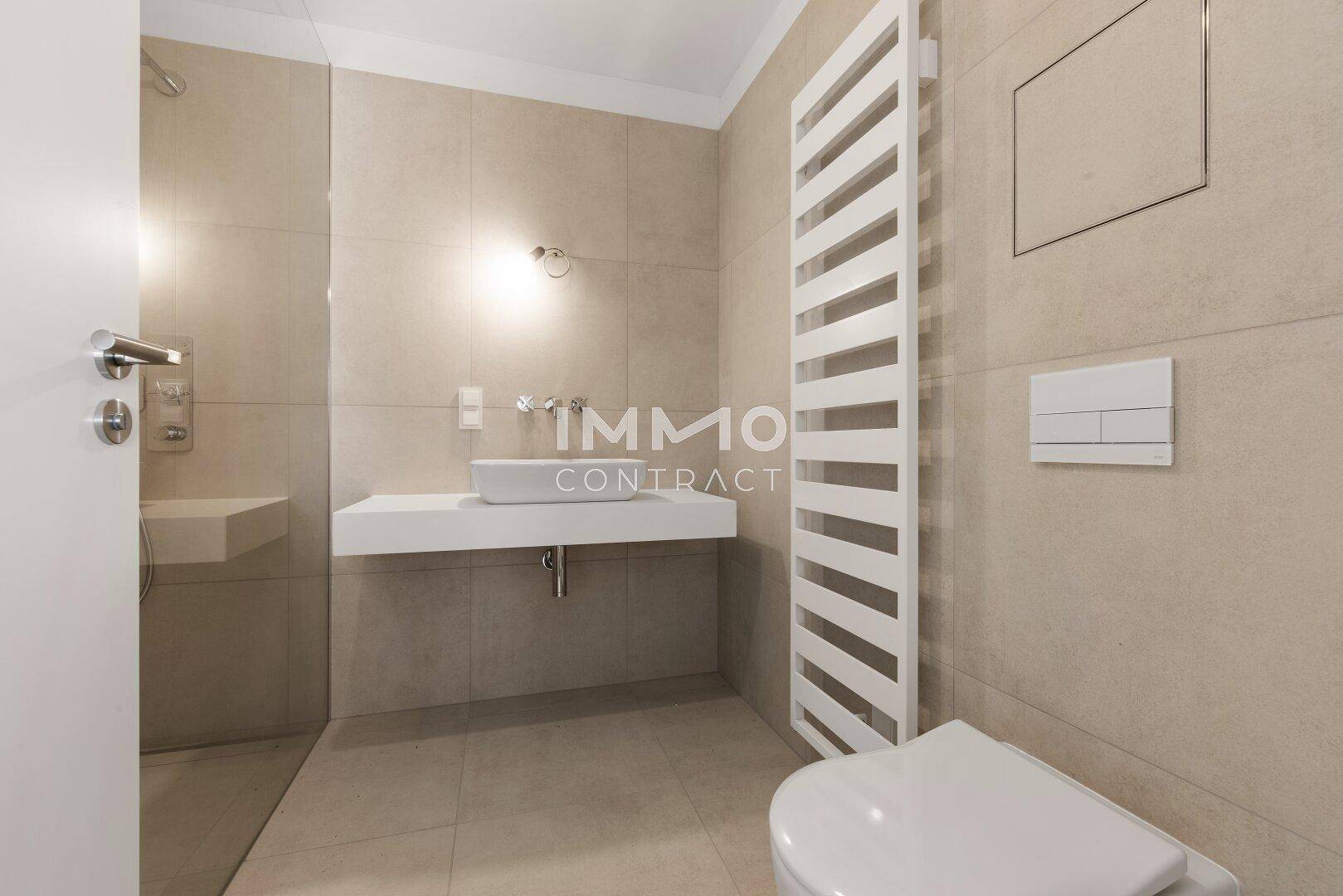 Modernes Badezimmer mit Waschtisch, wandhängender Toilette und beheiztem Handtuchhalter.