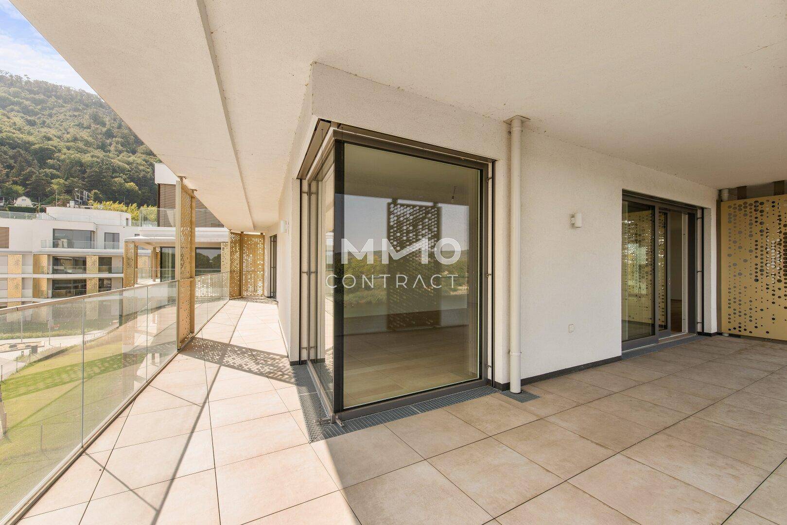 Breite Terrasse mit modernen Fliesen und großen Schiebetüren, die zum Innenbereich führen.