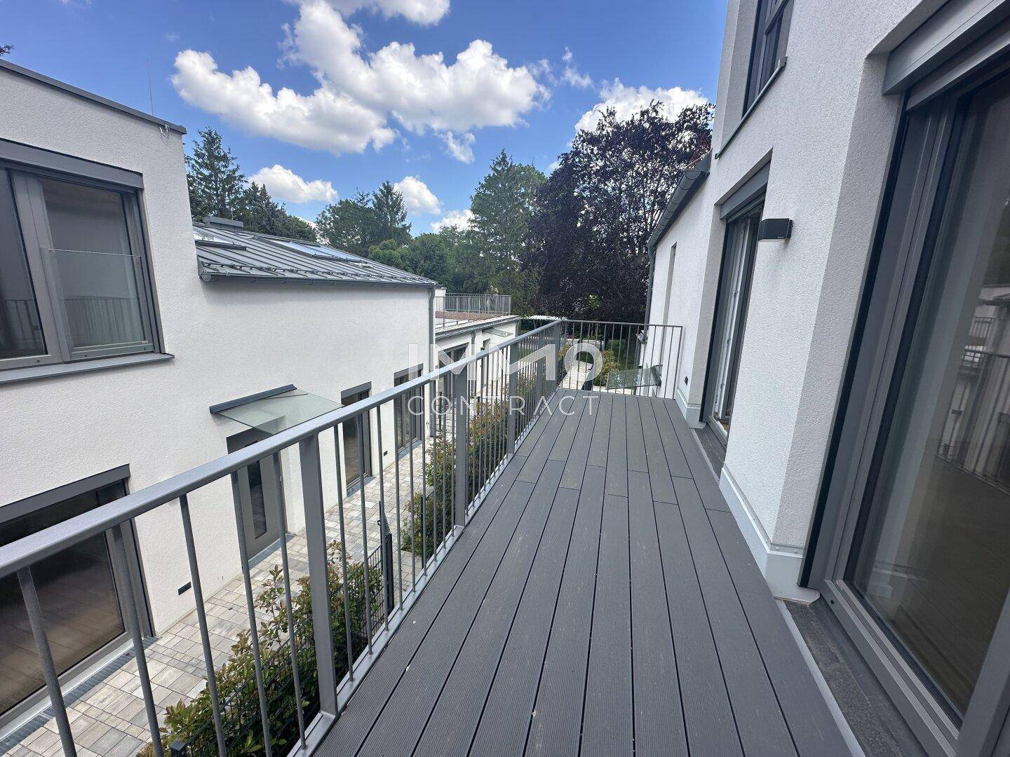 Langer Balkon mit Holzboden und Blick auf den Innenhof und die Nachbarschaft, bietet viel Platz im Freien.
