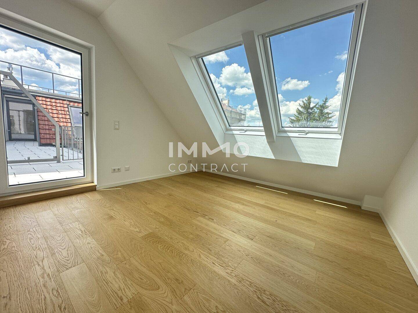 Unmöbliertes Schlafzimmer im Dachgeschoss mit Holzboden, Dachfenstern und Terrassenzugang, sehr hell.