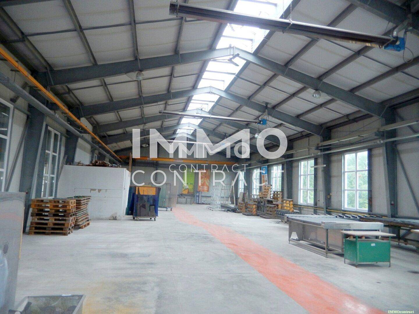 Weitläufige Lagerhalle mit Metallkonstruktion, Oberlichtern und Betonboden, ideal für industrielle Nutzung.