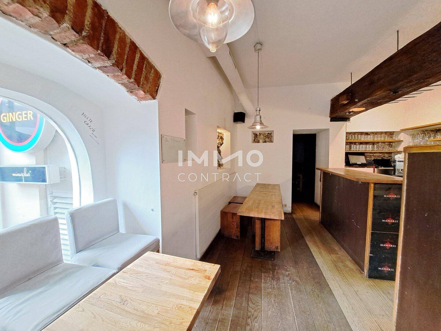 Gemütlicher Gastraum mit Holzboden, Sitzbänken und einer Theke, ideal für ein Café oder eine Bar.
